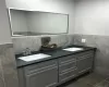 Bathroom featuring backsplash, double sink vanity, tile walls, and tile floors