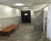 Hallway featuring dark tile flooring, tile walls, and a drop ceiling