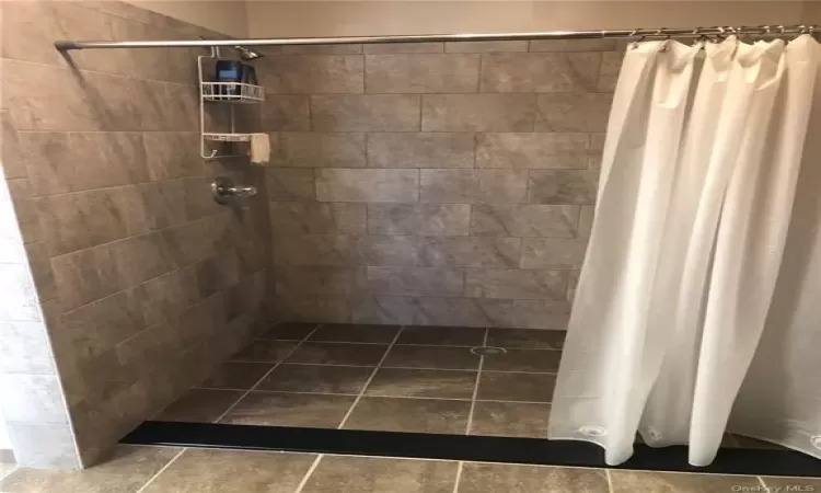 Bathroom featuring curtained shower and tile flooring