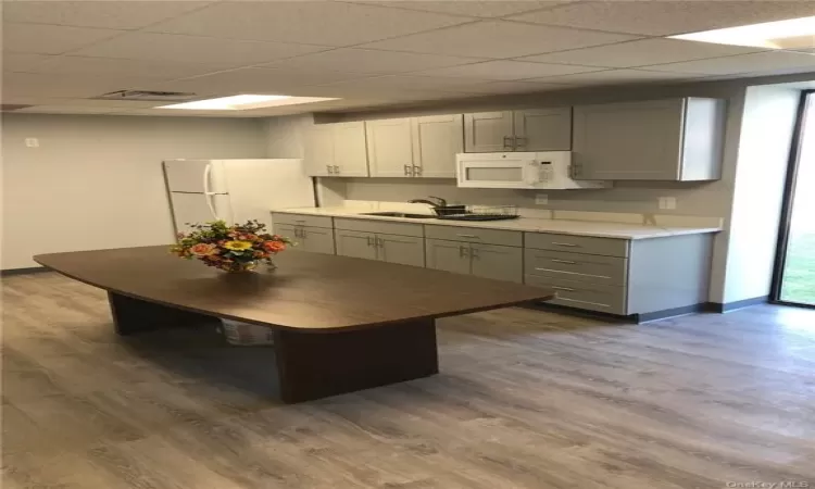 Kitchen with gray cabinets, hardwood / wood-style flooring, white appliances, and a drop ceiling