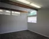 Carpeted spare room featuring lofted ceiling with beams