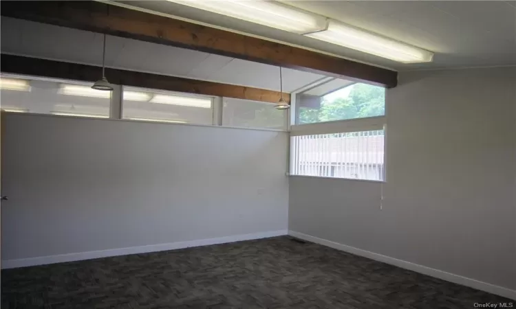 Carpeted spare room featuring lofted ceiling with beams