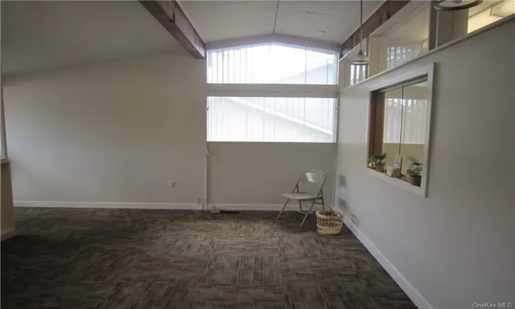 Unfurnished room with high vaulted ceiling, beam ceiling, and dark colored carpet