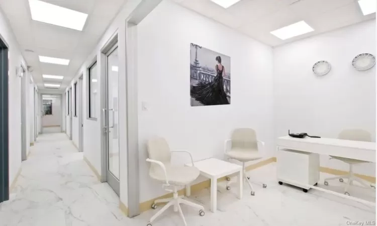 Corridor featuring a paneled ceiling and light tile flooring