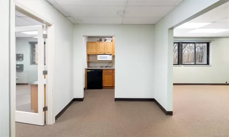 Hall featuring main office space to right, kitchen setup and private office to left