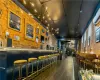 Bar featuring an AC wall unit, dark wood-type flooring, track lighting, and brick wall