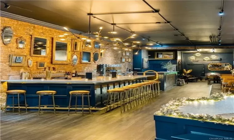 Kitchen with brick wall, a kitchen breakfast bar, wood-type flooring, and rail lighting