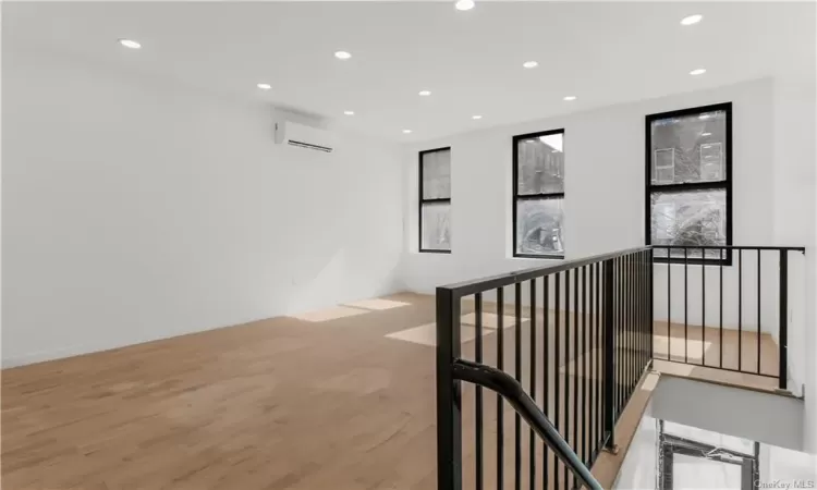 Hall with an AC wall unit and light hardwood / wood-style floors