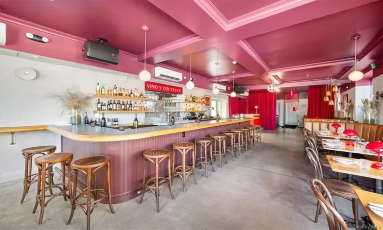 Bar with concrete flooring, beam ceiling, pendant lighting, a wall mounted air conditioner, and coffered ceiling