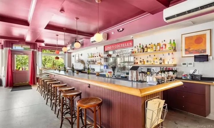 Bar with decorative light fixtures, a wall mounted AC, and coffered ceiling