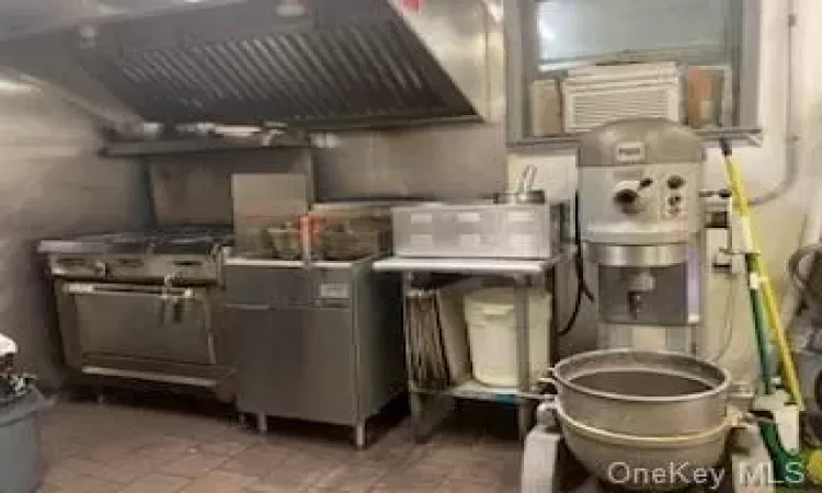 Kitchen featuring stainless steel counters, tile patterned floors, and custom range hood