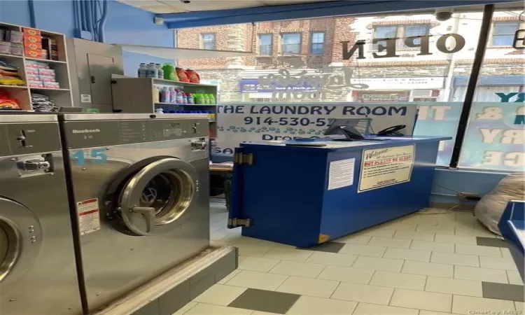 Laundry area featuring washer / clothes dryer, electric panel, and light tile patterned floors