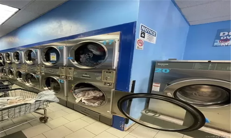 Laundry room featuring light tile patterned flooring and stacked washing maching and dryer