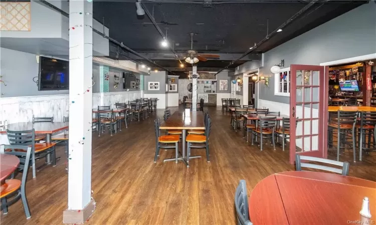 Dining area with hardwood / wood-style flooring, ceiling fan, and a towering ceiling