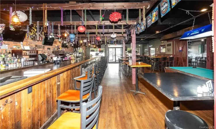 Bar with hardwood / wood-style flooring and billiards