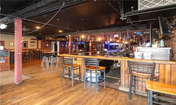 Bar featuring light hardwood / wood-style flooring and pendant lighting