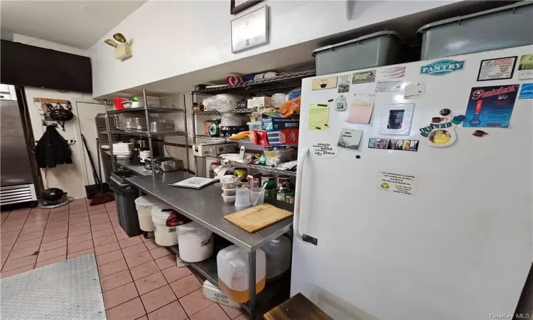 Kitchen with light tile patterned floors and refrigerator