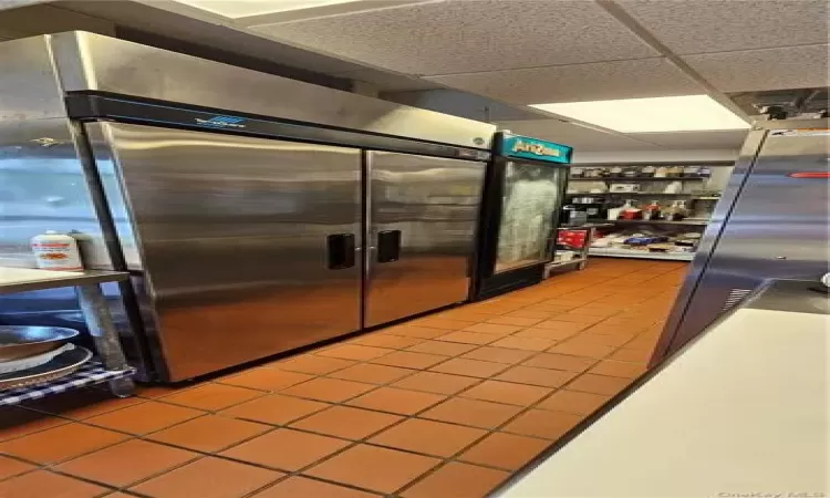 Kitchen featuring tile patterned floors, high end fridge, a paneled ceiling, and tile countertops