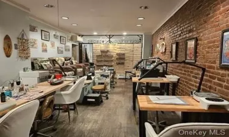 Rec room featuring brick wall, ornamental molding, and wood-type flooring