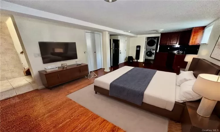 Virtually Staged Lower Level - Staged as a Studio Bedroom featuring open kitchen with full bathroom with stacked washer and clothes dryer and a textured ceiling