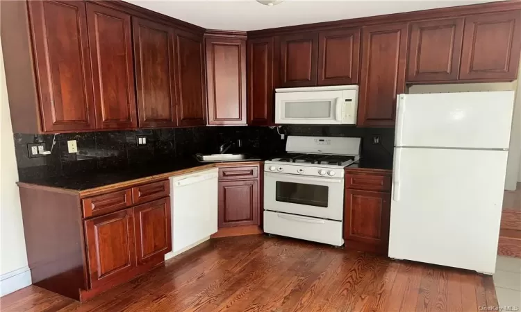 1st Floor - Open Concept Kitchen with white appliances, dark hardwood / wood-style floors, tasteful backsplash, and sink