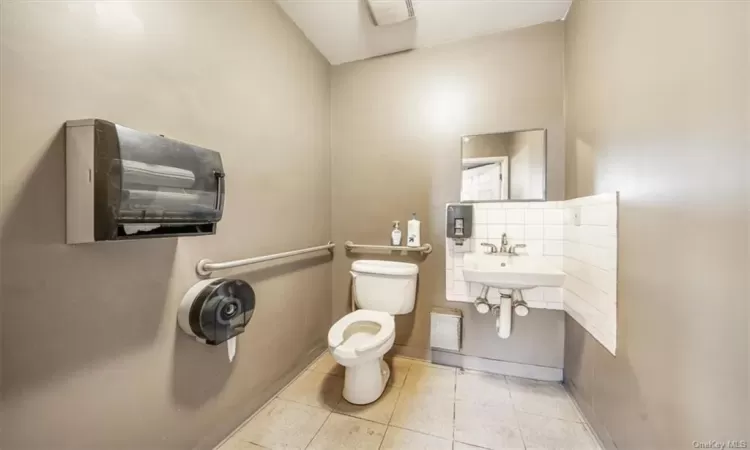 Bathroom featuring sink, decorative backsplash, and toilet