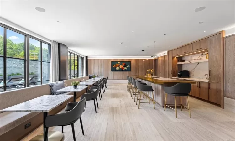 Kitchen with sink, pendant lighting, light hardwood / wood-style floors, a breakfast bar area, and wooden walls