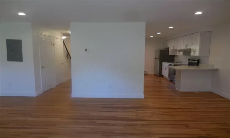 Kitchen with white cabinetry, stainless steel range with electric stovetop, electric panel, dark hardwood / wood-style floors, and white refrigerator