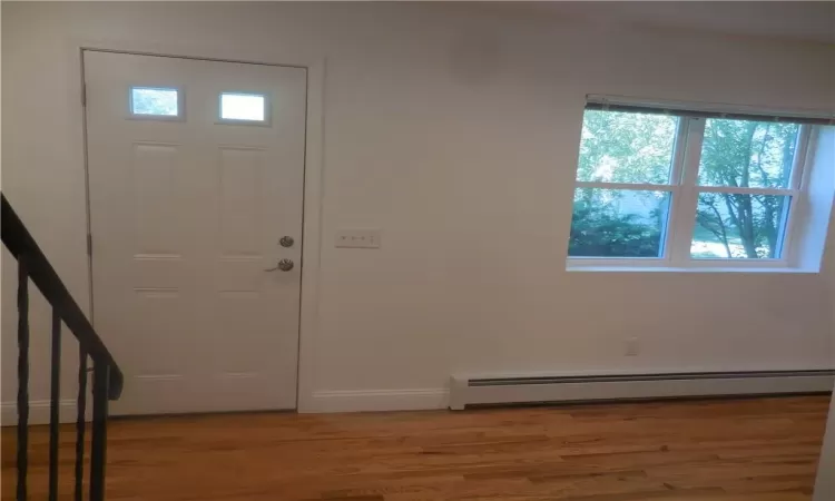 Entrance foyer with baseboard heating and hardwood / wood-style floors