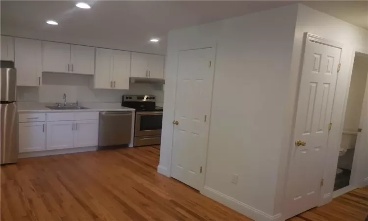 Kitchen featuring sink, stainless steel appliances, hardwood / wood-style floors, and white cabinets