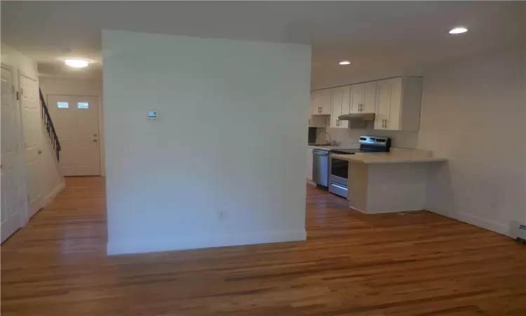 Kitchen featuring white cabinets, dark hardwood / wood-style floors, baseboard heating, appliances with stainless steel finishes, and sink