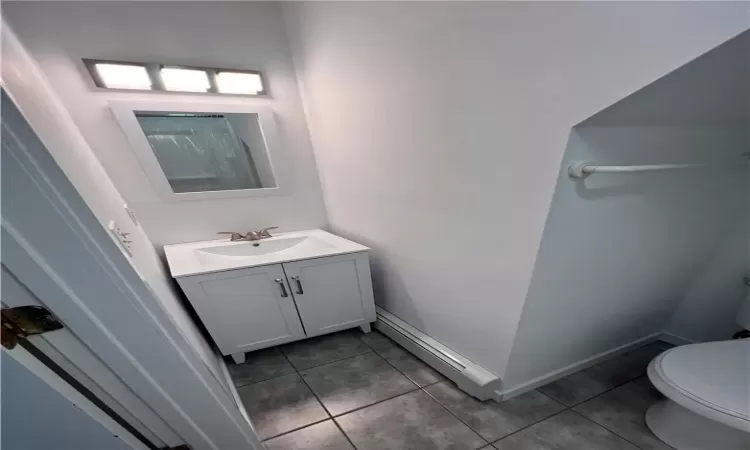 Bathroom with tile patterned floors, toilet, vanity, and a baseboard radiator