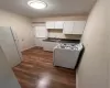 Kitchen featuring white cabinetry, refrigerator, dark hardwood / wood-style flooring, white stove, and sink