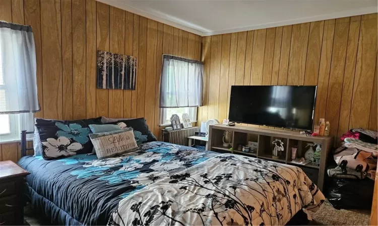 Bedroom with crown molding and wooden walls