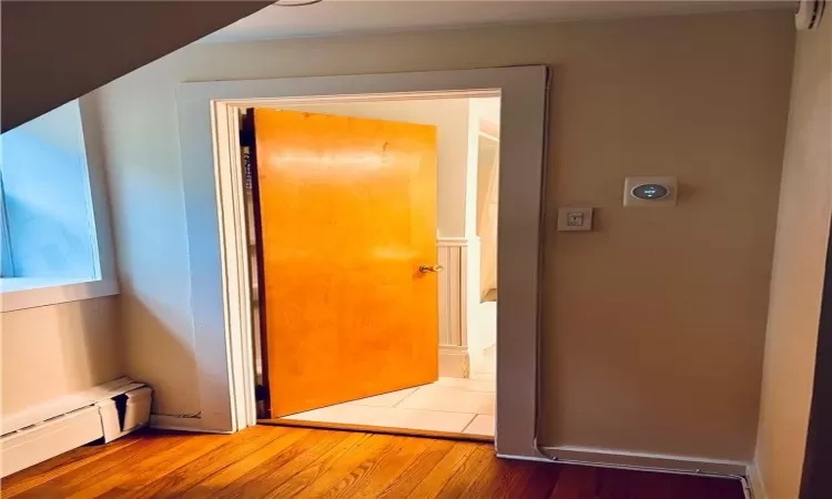 Corridor featuring wood-type flooring and a baseboard heating unit