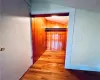 Corridor with wooden walls, vaulted ceiling, and hardwood / wood-style flooring