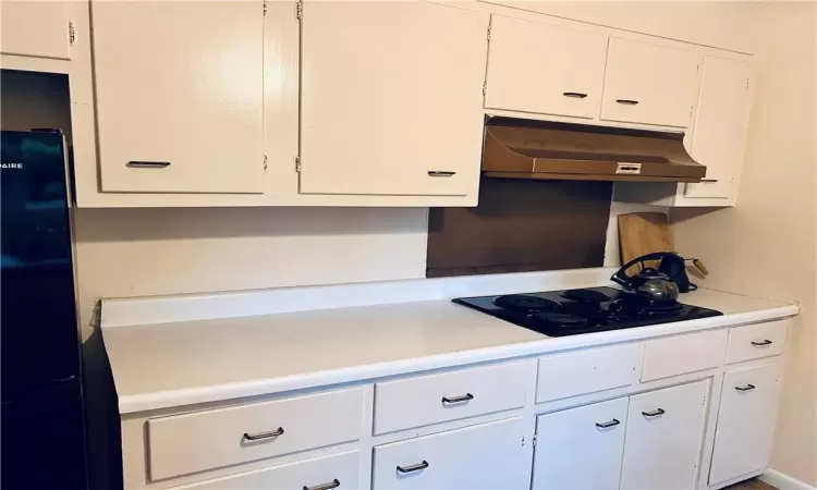 Kitchen featuring black appliances and white cabinetry