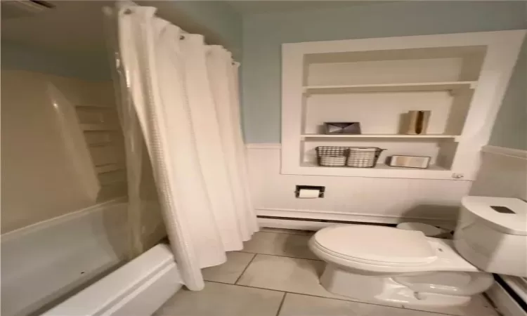 Bathroom with tile patterned flooring, toilet, and shower / tub combo with curtain