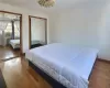 Bedroom featuring hardwood / wood-style flooring, cooling unit, and multiple closets