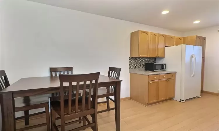 Kitchen featuring tasteful backsplash, light wood-type flooring, light brown cabinetry, and white fridge