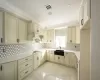 Kitchen with sink, cream cabinets, tasteful backsplash, and hanging light fixtures