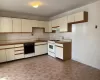 Kitchen featuring black dishwasher, cream cabinetry, sink, and white gas stove