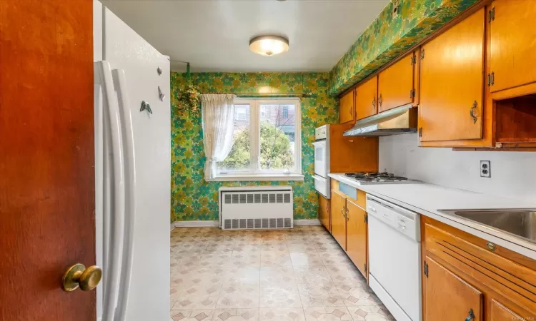 Kitchen with white appliances, radiator, and sink