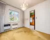 Carpeted empty room featuring radiator heating unit, an inviting chandelier, and a wall unit AC