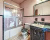 Full bathroom with vanity, enclosed tub / shower combo, tile walls, and toilet