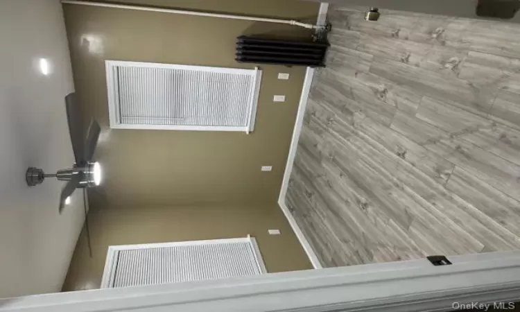 Spare room with ceiling fan, radiator, and light hardwood / wood-style flooring