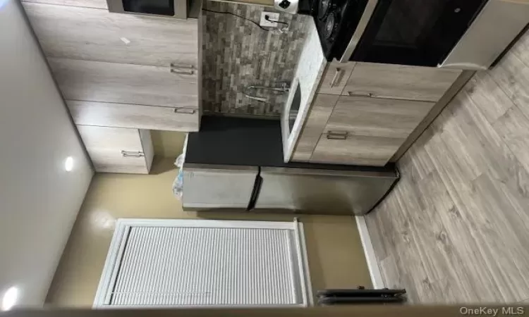 Kitchen featuring stove, sink, stainless steel fridge, light hardwood / wood-style floors, and radiator heating unit