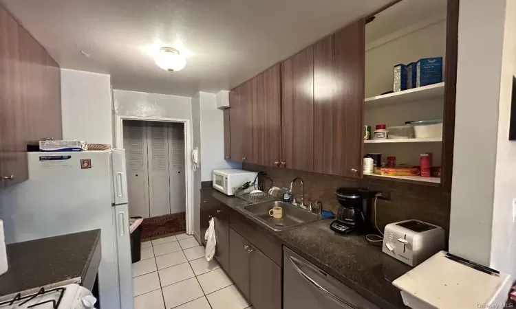 Kitchen featuring dark brown cabinetry, sink, tasteful backsplash, white appliances, and light tile patterned flooring