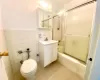 Full bathroom featuring tile patterned flooring, tile walls, toilet, enclosed tub / shower combo, and vanity