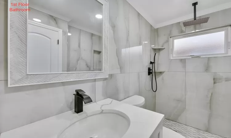 Bathroom with vanity, toilet, crown molding, and a tile shower